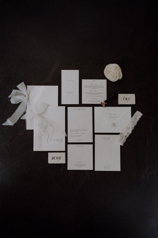 Stilvolle Hochzeitspapeterie in Cremefarben auf dunklem Hintergrund arrangiert.